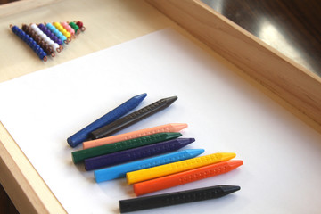 Naklejka premium Crayons and a blank sheet of paper on a tray with the Montessori colored bead stair
