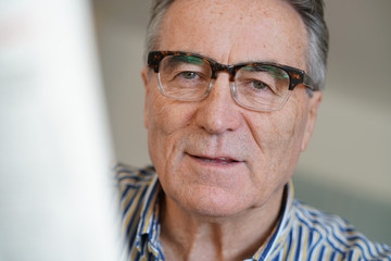 Senior man with eyeglasses reading newspaper