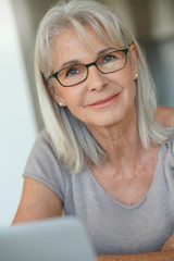 Senior woman with eyeglasses using laptop