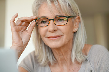 Senior woman with eyeglasses using laptop