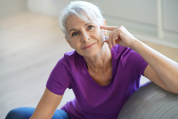 Senior woman sitting by fitness ball