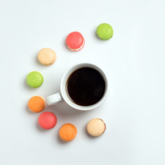 Obraz na płótnie Canvas Sweet and colourful macaroons with cup of coffee on white background. Traditional french dessert. Top view, flat lay, space for text