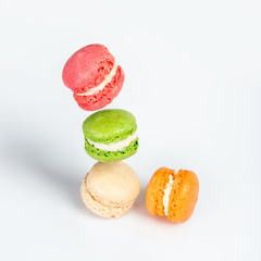 Different types of macaroons in motion falling on white background. Traditional french dessert isolated on white with space for text.