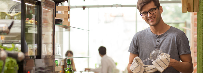 Barman polishing glass in coffeehouse