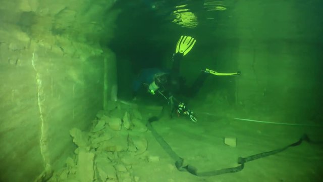 Speleologist swims along the corridor of flooded mine.

