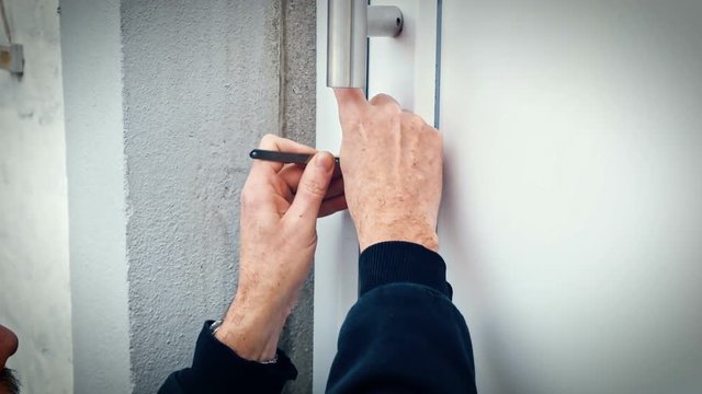 Intruder or Burglar with lockpick tool opens the front door to enter the house. could also be used for key service or locksmith concept