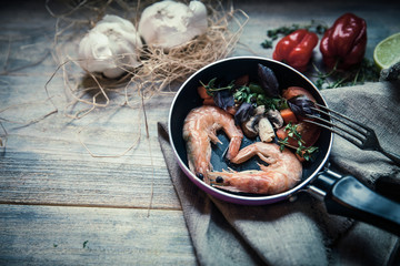 Romantic dish: prawns with colorful bell peppers, vegetables, basil, tomatoes in pan with sauce in St Valentines day