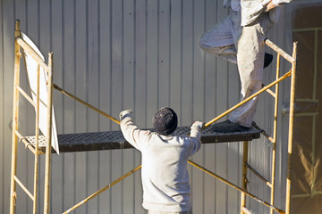  painters worker men in scaffolding for restoir, repair and pain