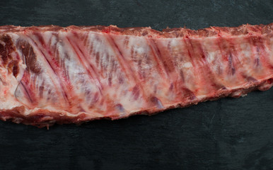 Raw pork ribs on black stone background,