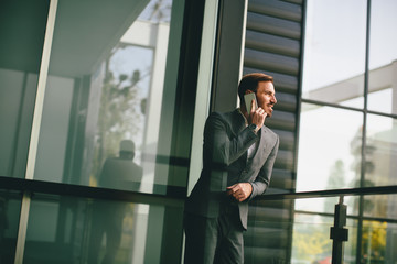 Young man with mobile phone by office building