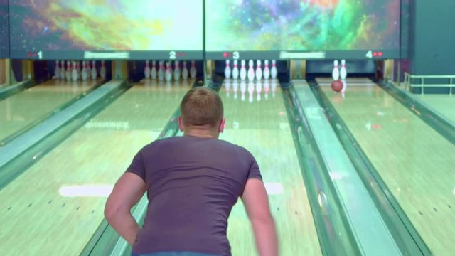 Blond guy moonwalking at the bowling alley. Close up of young male bowler going backward near the lane. Attractive caucasian man missing the target