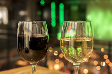 Red and white wine glasses on blurred lights background