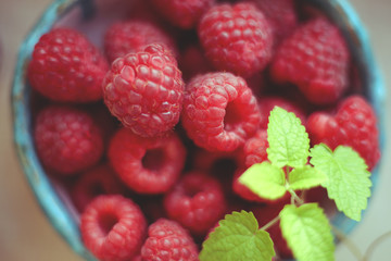 Macro raspberries in ceramic bowl. Tasty red berries with mint leaves
