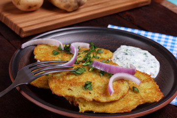 Potato pancakes with slice of onion on the dark plate