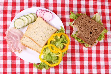 Sandwich with bacon and vegetables on the table with tablecloth