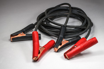 Cables for batteries with the positive and negative terminals on a light background.