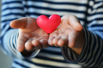child holding a small pink heart. symbol of love, family, hope. Backgrounds for cards on Valentine's Day. Backgrounds for social posters about the preservation of the family and children.
