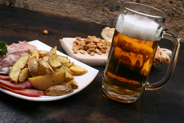 Light beer with foam snack, country style potatoes, sausage on the plate.