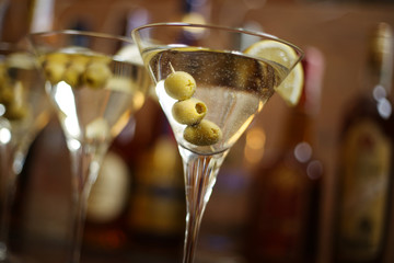 Martini glasses in the bar. Alcohol cocktails with olives and lemon slice