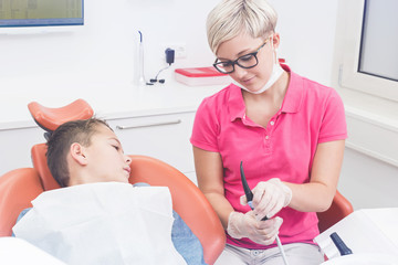 Junge schaut Zahnarzthelferin beim vorbereiten der Geräte zu