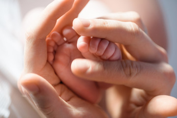 Cute tiny baby feet in father's hands comparison