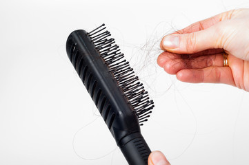 Fototapeta na wymiar Hair loss - pulling hair out of the plastic hair brush by hand