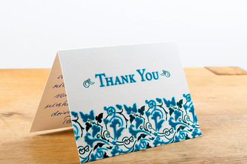 White thank you card with blue letters with note written by hand 
