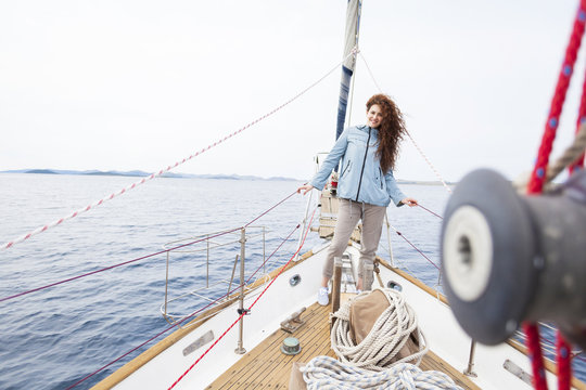Young woman stands on bow of yacht
