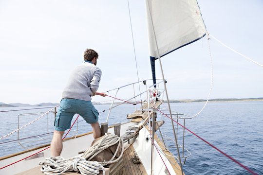 Man pulling on rope on yacht