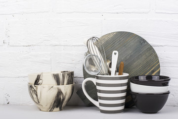 Simple modern kitchen still life in monochrome marble bowls, gray striped circle, round cutting board, ceramic  against a white brick wall. The horizontal