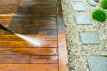 cleaning terrace with a power washer - high water pressure cleaner on wooden terrace surface