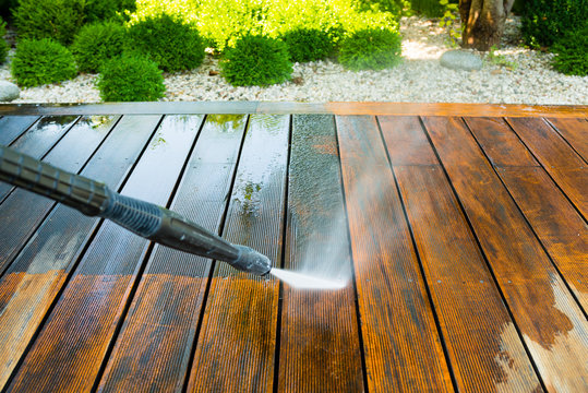 cleaning terrace with a power washer - high water pressure cleaner on wooden terrace surface