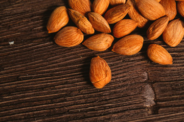 Apricot kernels are scattered on the wooden background