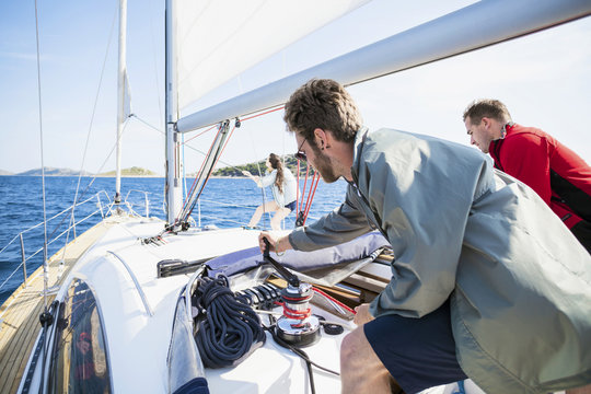 Two men turning cable winch on sail ship