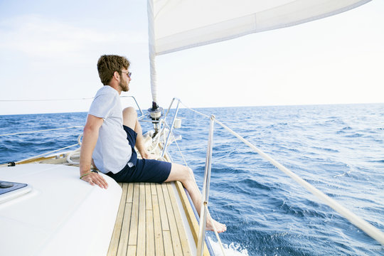 Man dangling feet from sail ship