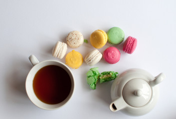 Cup of tea with french macaroon on white  background. Tea pot, cup of tea, color macaroon lying on white