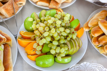 Fruit slices of apples, oranges, pears and grapes on a platter, catering