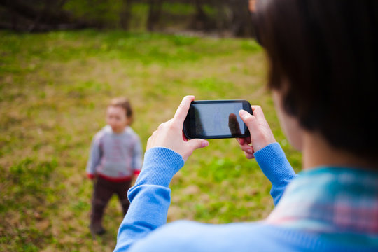 The girl makes a photo of the child on the smartphone.