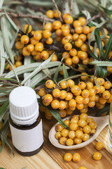 Sea-buckthorn oil and berries buckthorn branch in bowl on a wooden background. selective focus image 