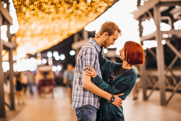 Happy couple embracing in the evening on a light garlands