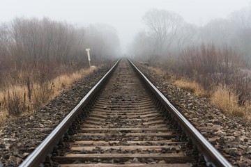 Fototapeta na wymiar Empty railroad track going into a fog, outdoor landscape