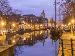 Dutch old city Schiedam landscape during calm weather with reflections in a canal, old barges and a church