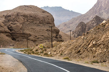 Old wooden electricity pylons nexto to road in Iran