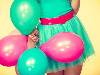 Woman holding bunch of colorful balloons