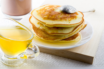 Pancakes with honey and vintage silver spoon on a white plate