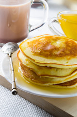 Mug of cocoa, silver spoon, honey and pancakes