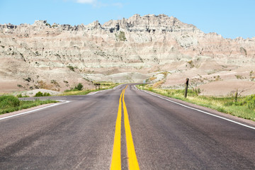 A road cutting through rolling hills in the Badlands of South Dakota on a summer day.  