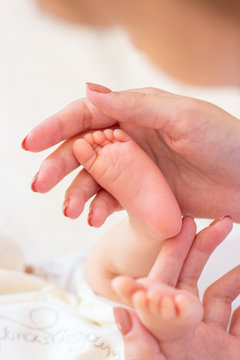 Close-up of legs, handles child. Happy mother kissing the feet, hands, fingers, the nose of the child. Gentle photo mom and baby.