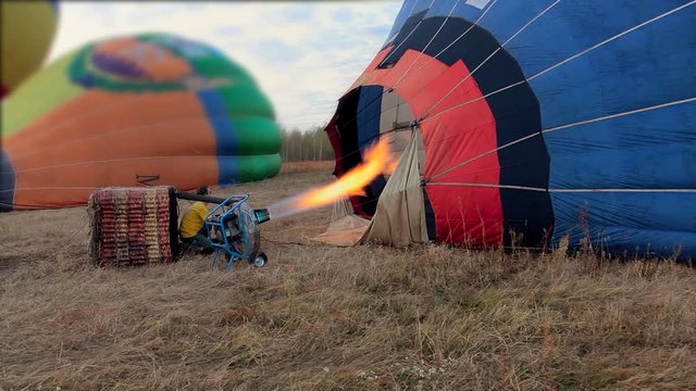 Propane gas burner filling balloon with hot air on the field