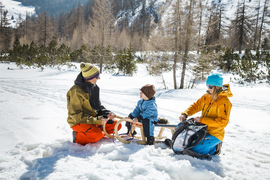 Family with sledge taking a break in snowy landscape